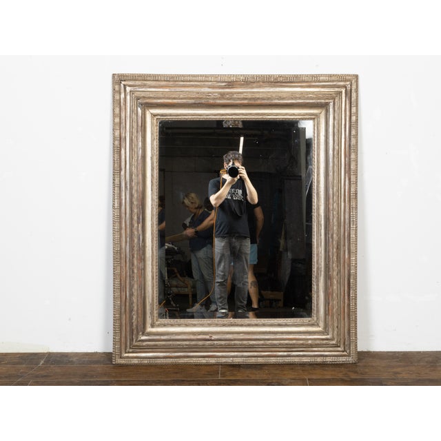 A Dutch rectangular mirror from the early 19th century with silver leaf décor, carved frame and beveled mirror plate....