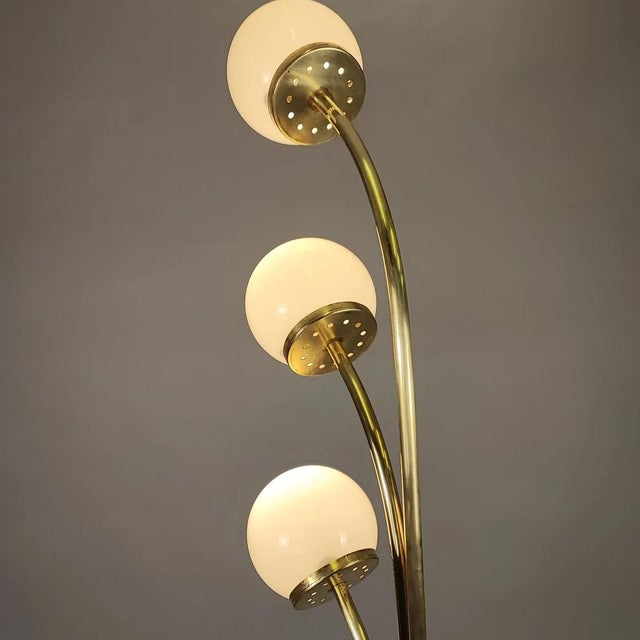 Floor lamp with a 70s design. Brass structure and three milky white opaline glass spheres. Two-position switch, mounts 3...