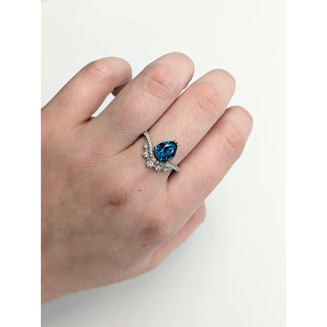A blue zircon glows in a brilliant electric blue at the centre of this solid 14K white gold ring, encircled by thirty-four...