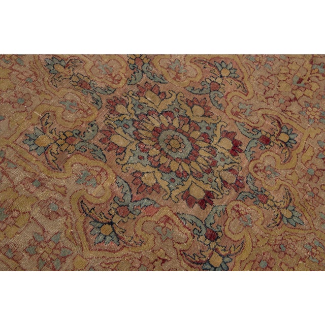 This stunning Kerman wool rug has been hand-knotted with antique craftsmanship. Its color field is a lovely tan. It is...
