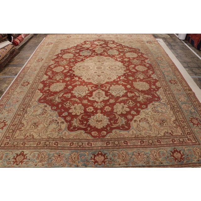 Hand-knotted in wool originating from Persia circa 1910-1920, this 10×14 antique rug connotes a Tabriz design in a...