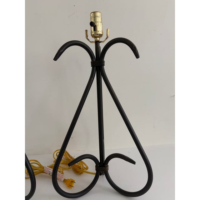This listing is for a pair of vintage wrought iron table lamps with tall open scrollwork frames and a black finish. The...