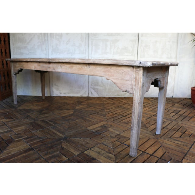 Beautiful antique farmhouse dining table crafted from solid pine, dating to the Early 20th century. The table features a...