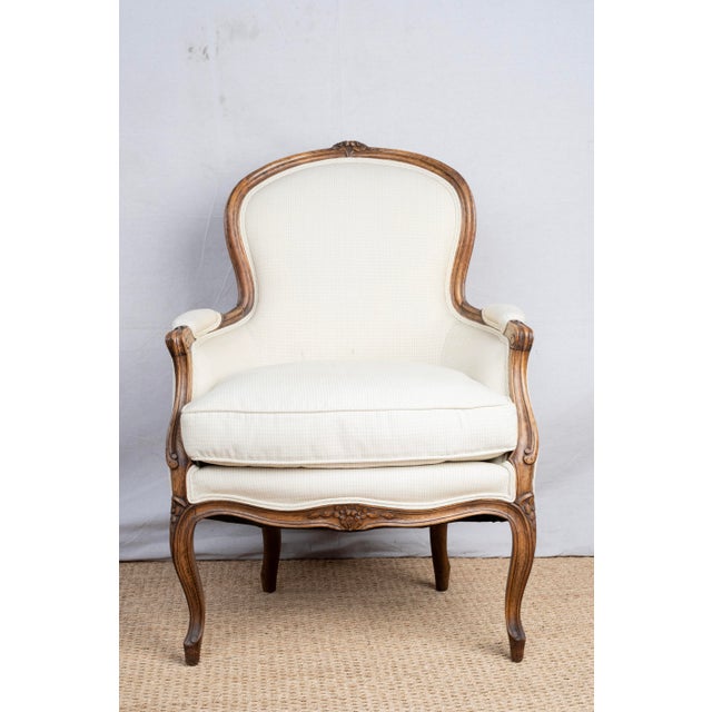An antique Bergère chair, c. 1820, French. Featuring enclosed arms with a loose seat cushion and upholstered and trimmed...
