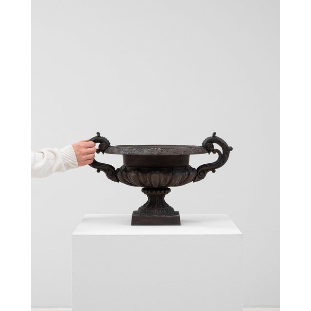 This urn carries genuine presence, its dark bronze/black cast metal, scrolled handles, larger immediately setting the tone...