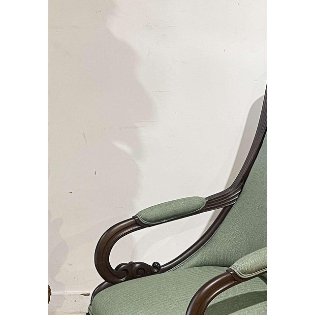 English lounge chair. English; made of mahogany wood; upholstered in green fabric. Rests on four curved legs. Dimensions:...
