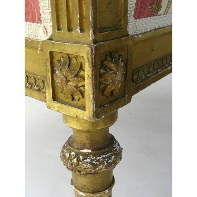 French carved gilt Louis XVI style bergere chair. Finial on back top. Measures 24" by 27" by 43". Some loses wear to gilt.