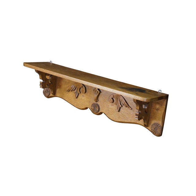 Antique hand-carved wooden wall shelf crafted from solid golden oak with a clear, prominent grain texture. It features a...