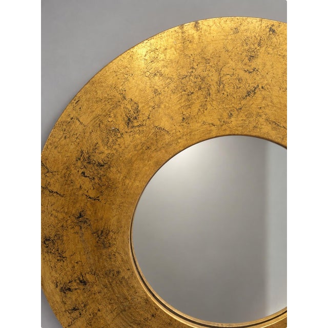 Round decorative wall mirror featuring a distressed black finish accented with warm gold tones. The layered finish gives...
