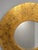 Round decorative wall mirror featuring a distressed black finish accented with warm gold tones. The layered finish gives...