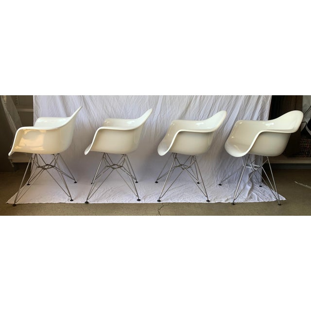 Set of 4 modern Eames-style white plastic armchairs. These classic mid-century style armchairs feature white molded...