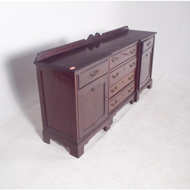 Sideboard with small elevation, in mahogany. In dark wood, it has three overlapping central drawers flanked by two doors,...