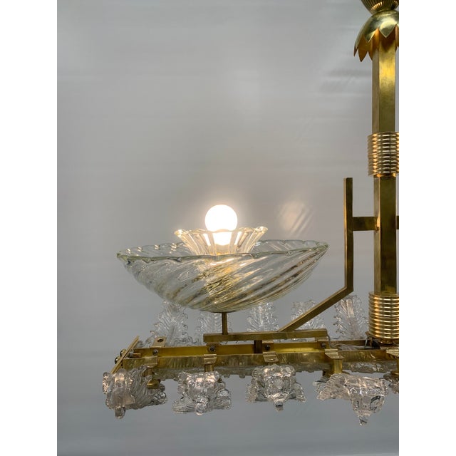 Art deco-style pendant lamp featuring a gold-finish brass frame and an elegant symmetrical composition. It features two...