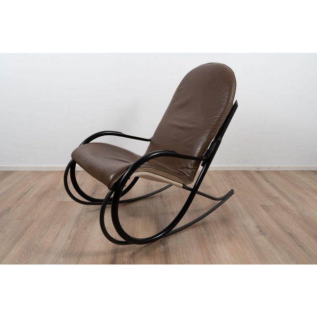 It has a black bentwood frame with a brown leather upholstery. This piece is attributed to the mentioned designer/maker....