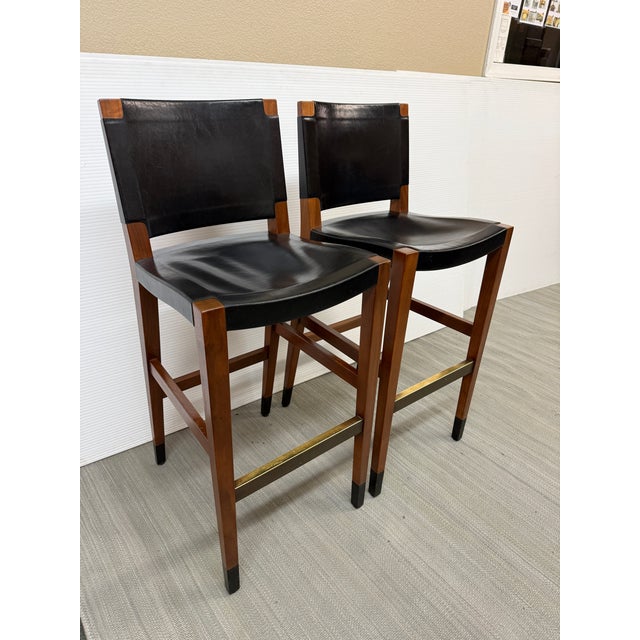 Design Plus Gallery presents a Pair of Walnut Wood and Leather Bar Stools. The duo has manly proportions with wide seats...