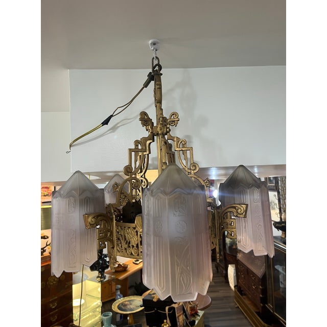 this vintage art deco chandelier featuring intricate brass detailing and frosted glass shades.