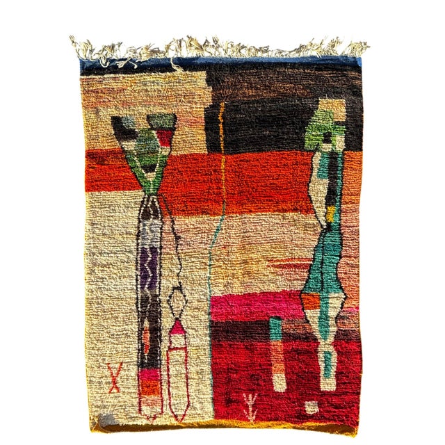 This contemporary Moroccan Boujad rug features a bold abstract composition combining warm tones of red, ochre, beige,...