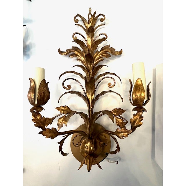 Pair of elegant, gilded scroll and leaf two-light sconces. The intricately crafted leaves grow naturally from the frame,...