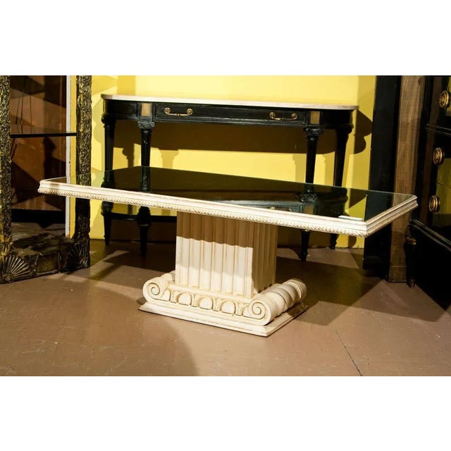 An exquisite coffee table, overall distress-painted, the rectangular top with glass inset supported by a pillar-shaped...