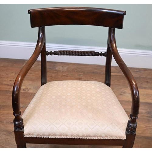 Attractive pair of Regency style mahogany chairs comprising one armchair and one side chair. Broad figured top rails are...