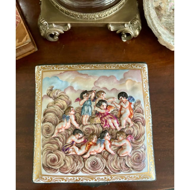 A magnificent hand-painted porcelain box richly decorated in the Italian Capo di Monte style with putti and cherubs in...