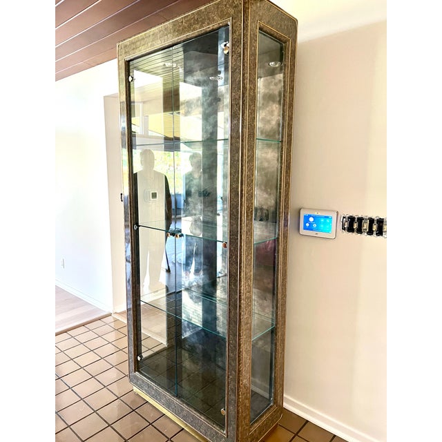 Mastercraft model 21-420 china cabinet vitrine. Clad in antiqued brass with black lacquer trim. Backwall is smoked...