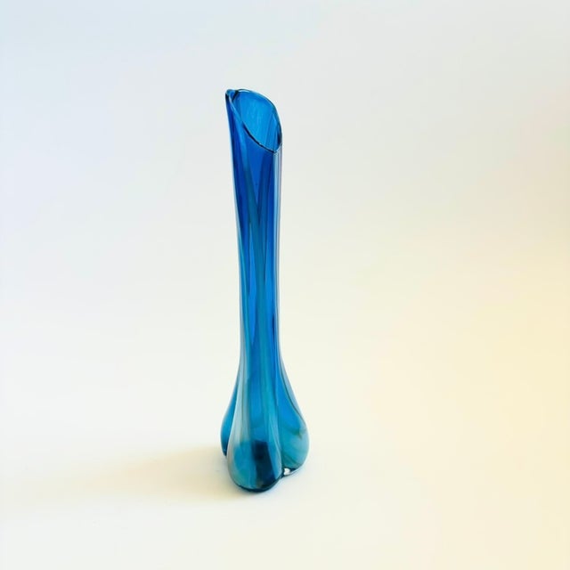 A mid century swung blown glass vase. Vibrant blue color to the glass with faint white striping. Measures 2.5"Dia x 10.5"H