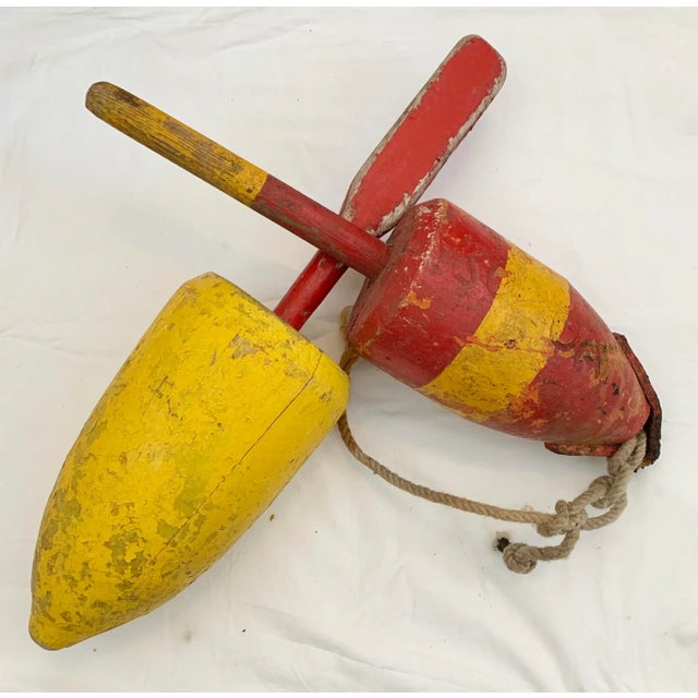 Weathered yellow and red painted wood buoys with carved identification numbers. Age wear, cracks, chipping paint. Smaller...