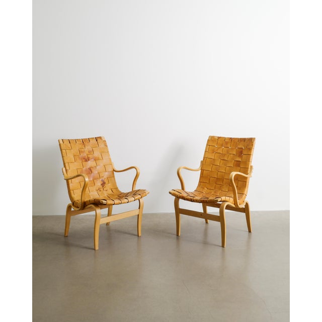 A rare and iconic pair of swedish mid century modern "eva" armchairs in form pressed birch wood and original woven leather...