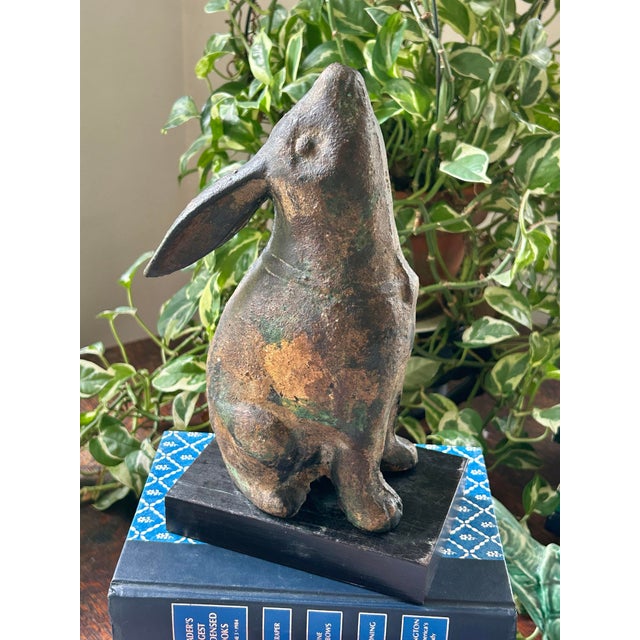 This is a vintage Japanese cast iron rabbit sculpture in a seated pose with floppy ears and a rounded, sculptural form....