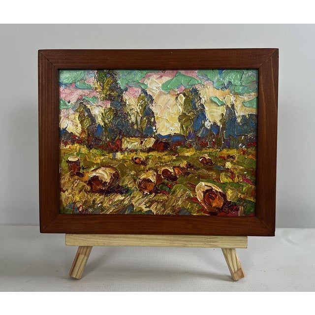 The oil painting on canvas titled "Haystacks in the Field" captures the rustic beauty of a harvested field bathed in the...