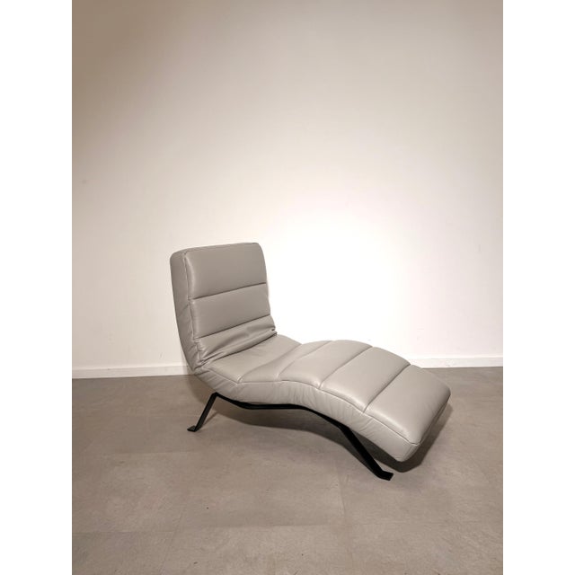Elegant modern chaise lounge upholstered in high-quality light grey leather. Its flowing ergonomic silhouette provides...