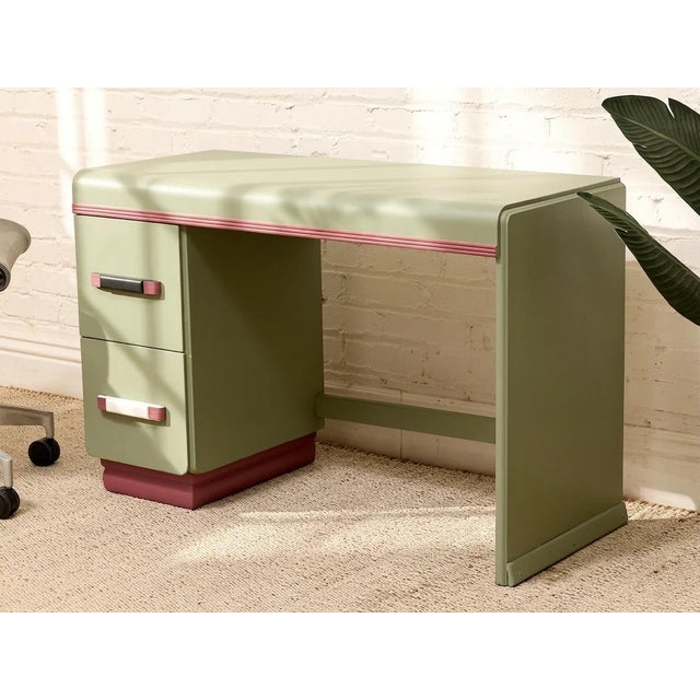 A charming vintage writing desk finished in soft mint green with warm wood-tone accent details. Its streamlined...