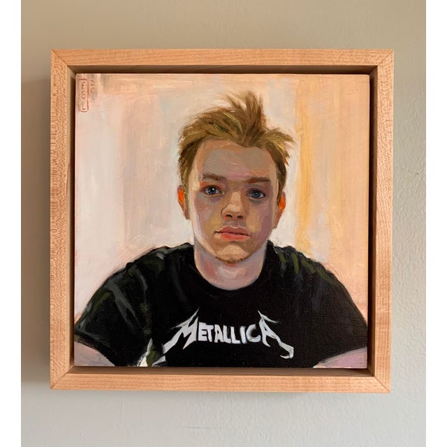 This oil on panel artwork features a young person wearing a Metallica t-shirt, captured in a moment of quiet...