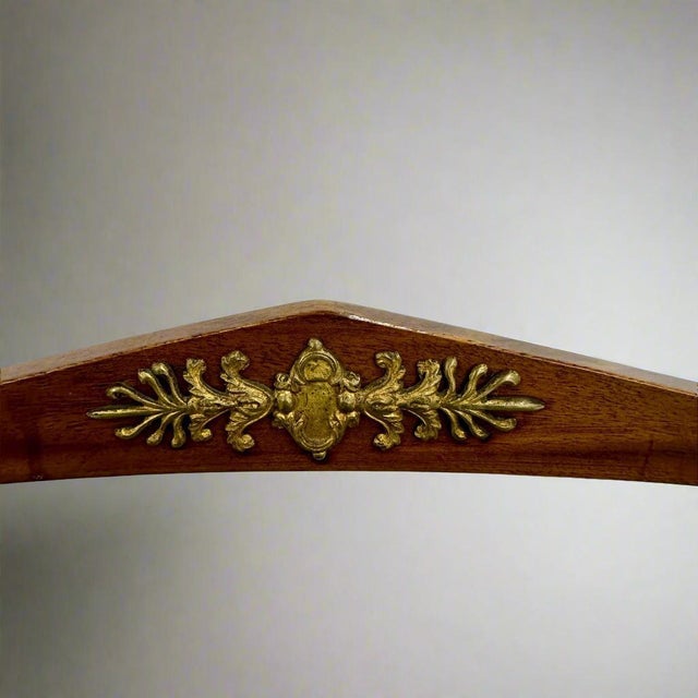 An elegant pair of Italian Neoclassical mahogany chairs adorned with patinated brass mounts from Italy. These chairs...