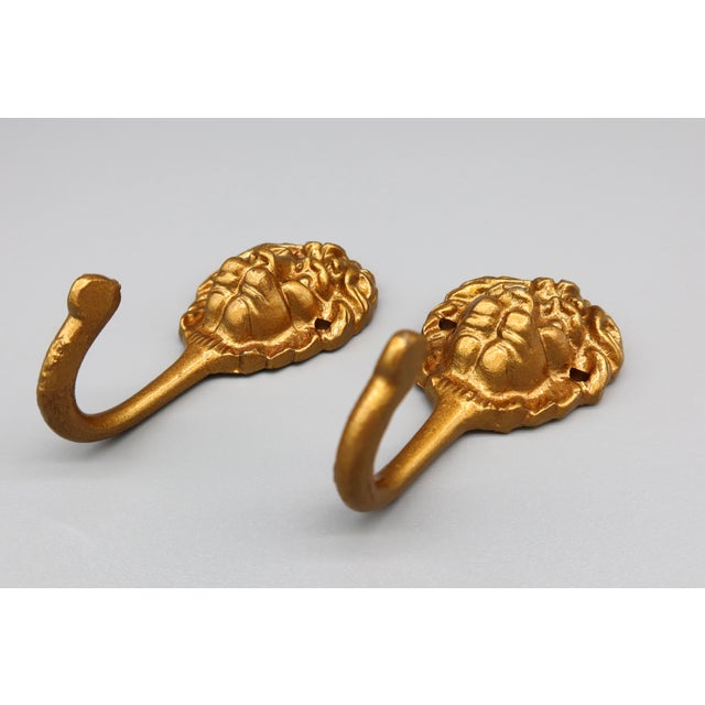 A pair of vintage brass lion head wall hooks, featuring bold, expressive detailing and a timeworn finish. Originally...