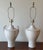 A pair of vintage ceramic table lamps in a classic urn form, finished in a smooth white glaze. Each features gently curved...