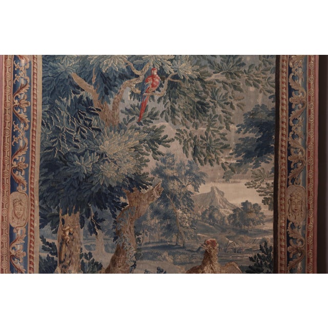 Polychrome tapestry depicting a flowering undergrowth with birds, including a parrot, against a mountain backdrop....