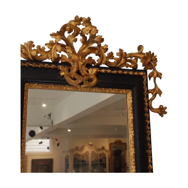 An elegant 19th-century French antique mirror combining giltwood and black finishes for a striking yet refined contrast....