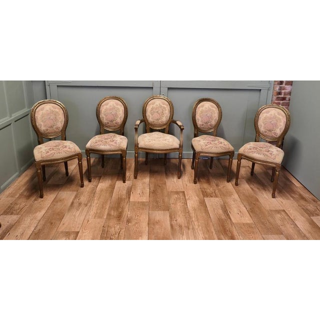 French Salon chairs circa 1880 in the Louis XVI style, 4 single and one carver chair The chairs have aged gold carved Gilt...