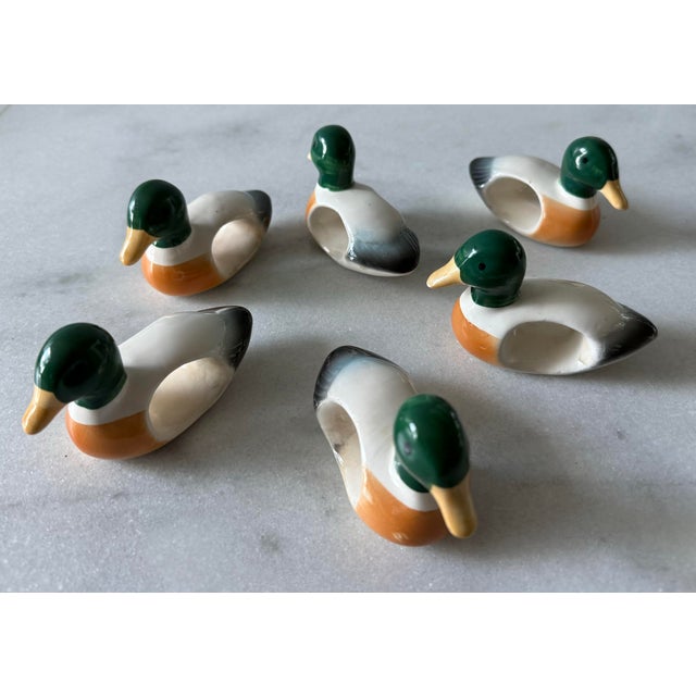 Set of 6 vintage ceramic napkin rings in the shape of mallard ducks featuring a green head, yellow bill and mottled body.