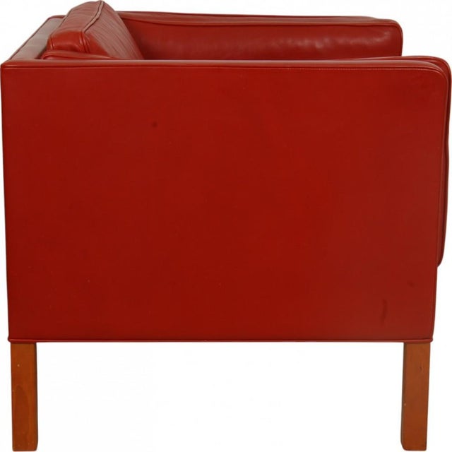 Børge Mogensen lounge chair model 2334 upholstered in red leather and with legs of cherry wood. The chair is from 2001 and...