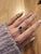 A tanzanite rests in a deep violet-blue at the heart of this solid 14K white gold ring, flanked by thirty-eight earth-...
