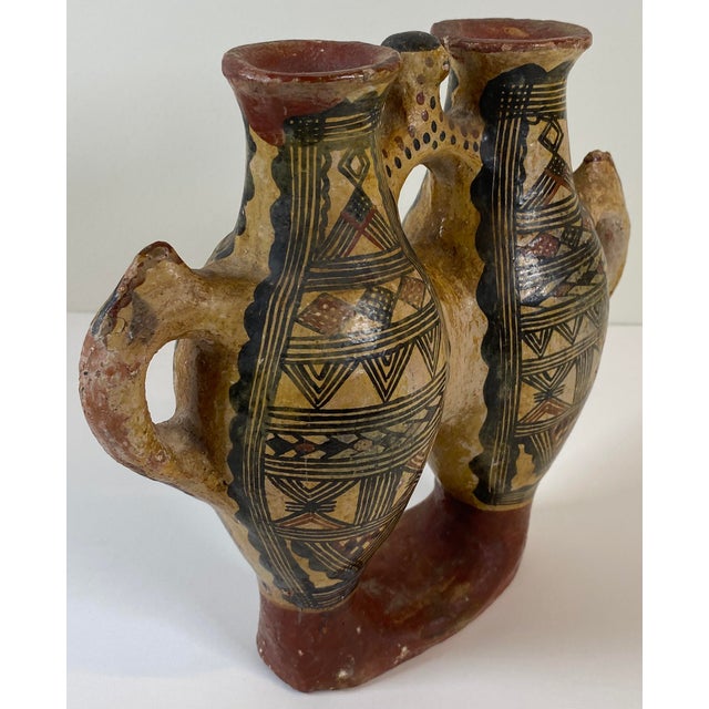This striking double‑chamber ceramic vessel features intricate hand‑painted geometric motifs in black and red on a warm...
