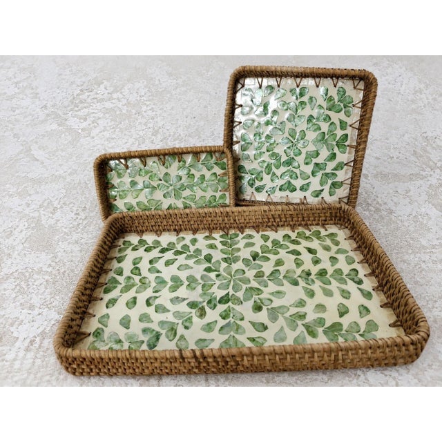 The three-piece nested rectangular tray is made of natural rattan with mother-of-pearl inlay. Craftsmen cut the mother-of-...