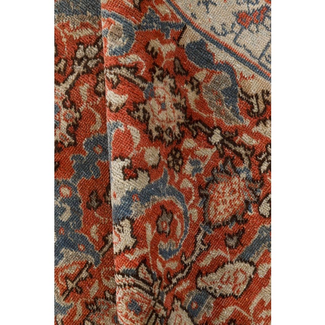 An early 20th century Persian Tabriz rug, the abrashed red field with an allover trellis of delicate flowering vine, taupe...