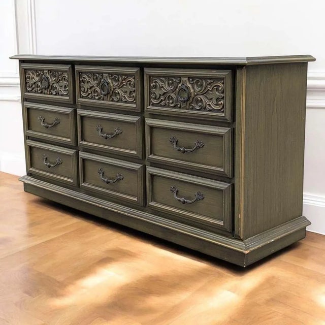 A dramatic 1970s Spanish Revival lowboy with nine drawers, richly carved wood detailing, and a distinctive olive-green...