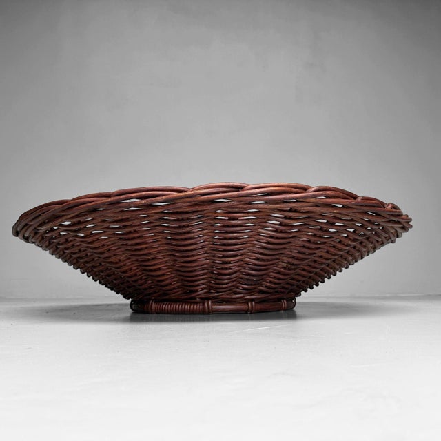 An exceptionally large Japanese basket bowl with a low, wide shape and beautifully rhythmic weaving in warm reddish-brown...