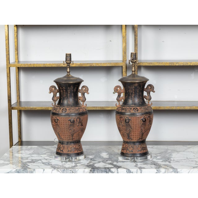 A pair of Asian bronze urn-shaped table lamps from the mid 20th century, with brown and black patina, mythical animals...