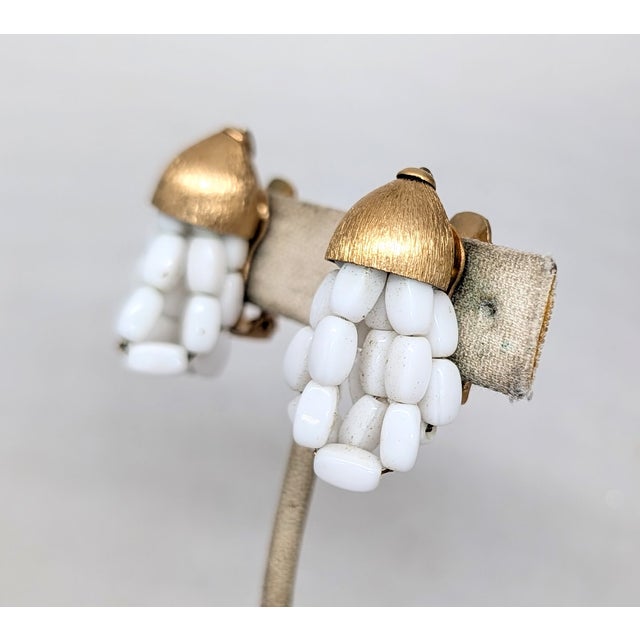 1960s goldtone Florentine finish top with looped white glass bead dangles clip earrings. Marked "NAPIER PAT. PEND" on the...